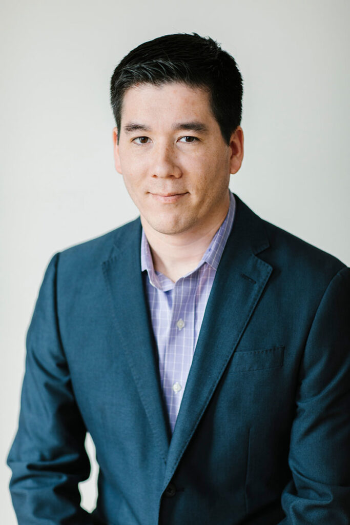 headshot of Nick Foss in navy suit jacket and purple checkered shirt